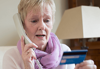 older woman gives credit card details on the phone