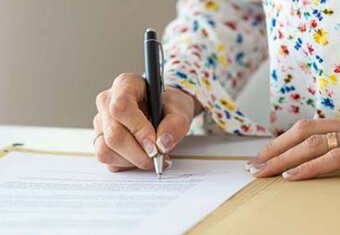 Image of woman signing document.