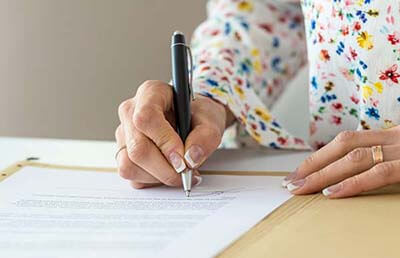 Image of woman signing document.